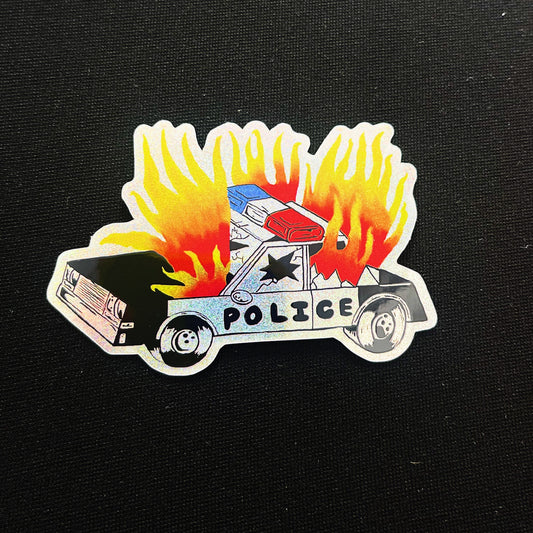 A die-cut sticker featuring a cartoon-style police car engulfed in flames